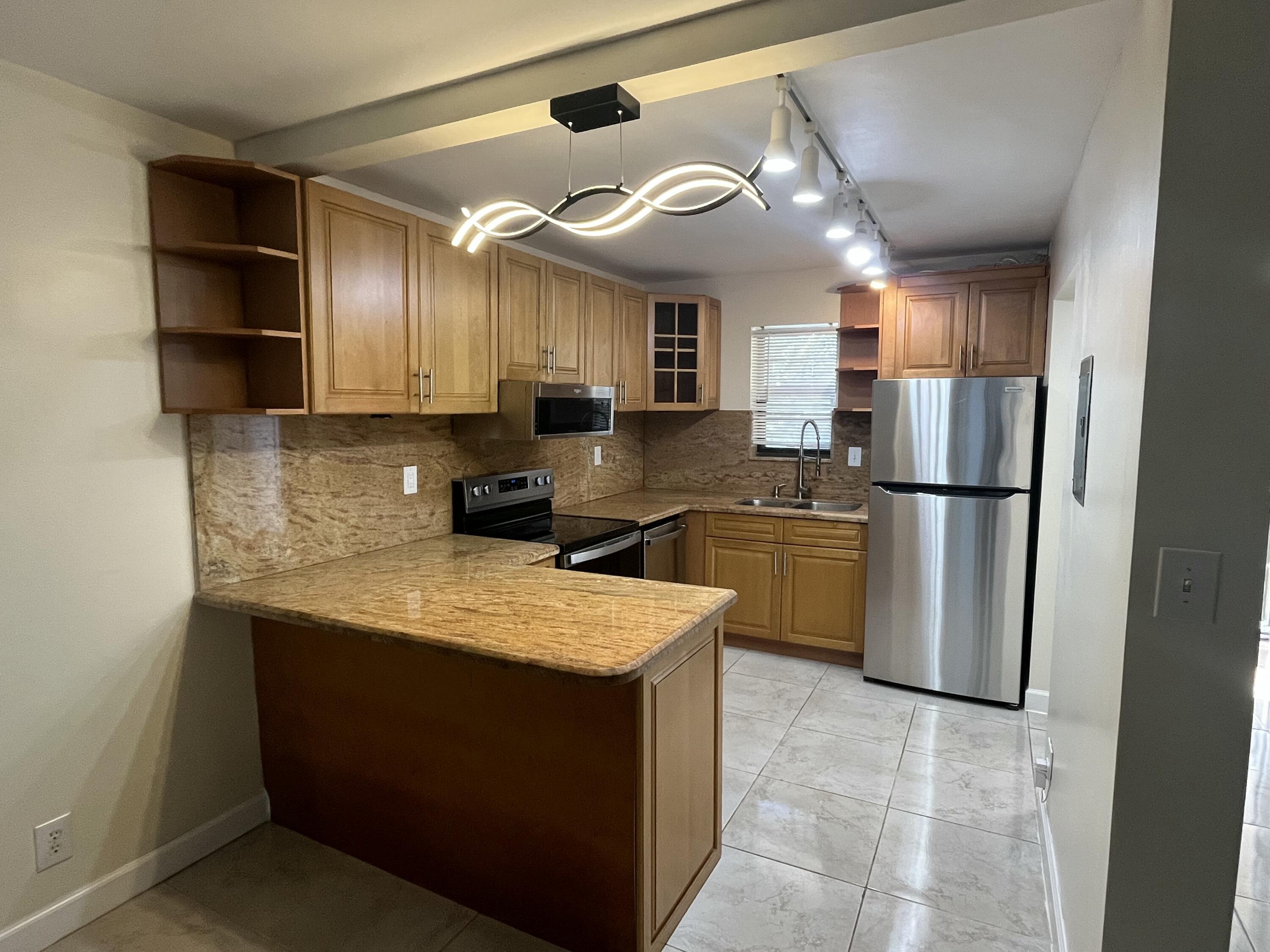 9300 Southwest 8th Street, Unit 301 Boca Raton, FL 33428 - Photo 4 of 27 a kitchen with stainless steel appliances granite countertop a refrigerator a sink a stove a microwave and island
