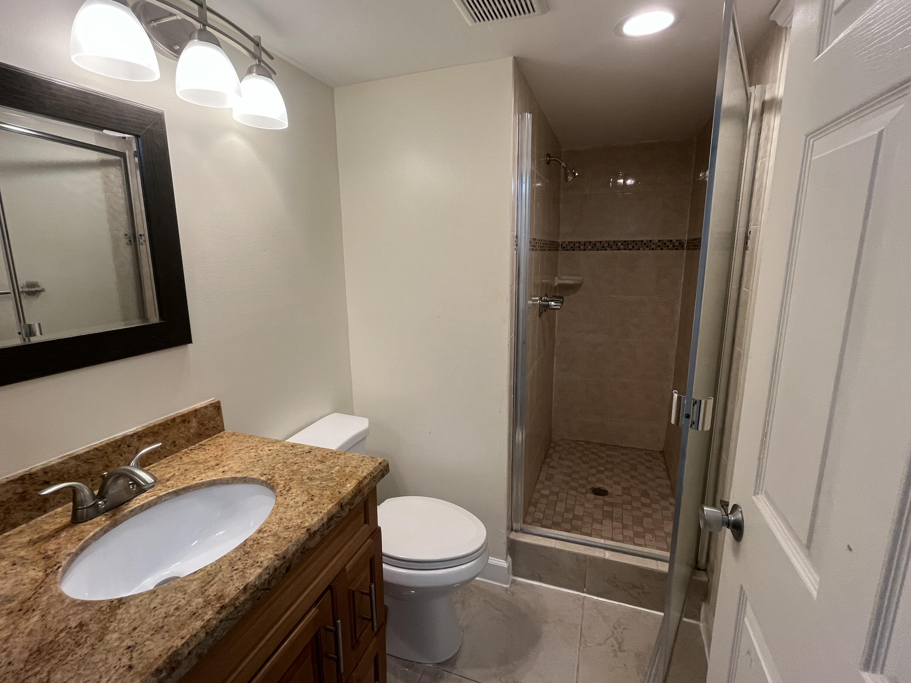 9300 Southwest 8th Street, Unit 301 Boca Raton, FL 33428 - Photo 9 of 27 a bathroom with a granite countertop sink toilet and shower