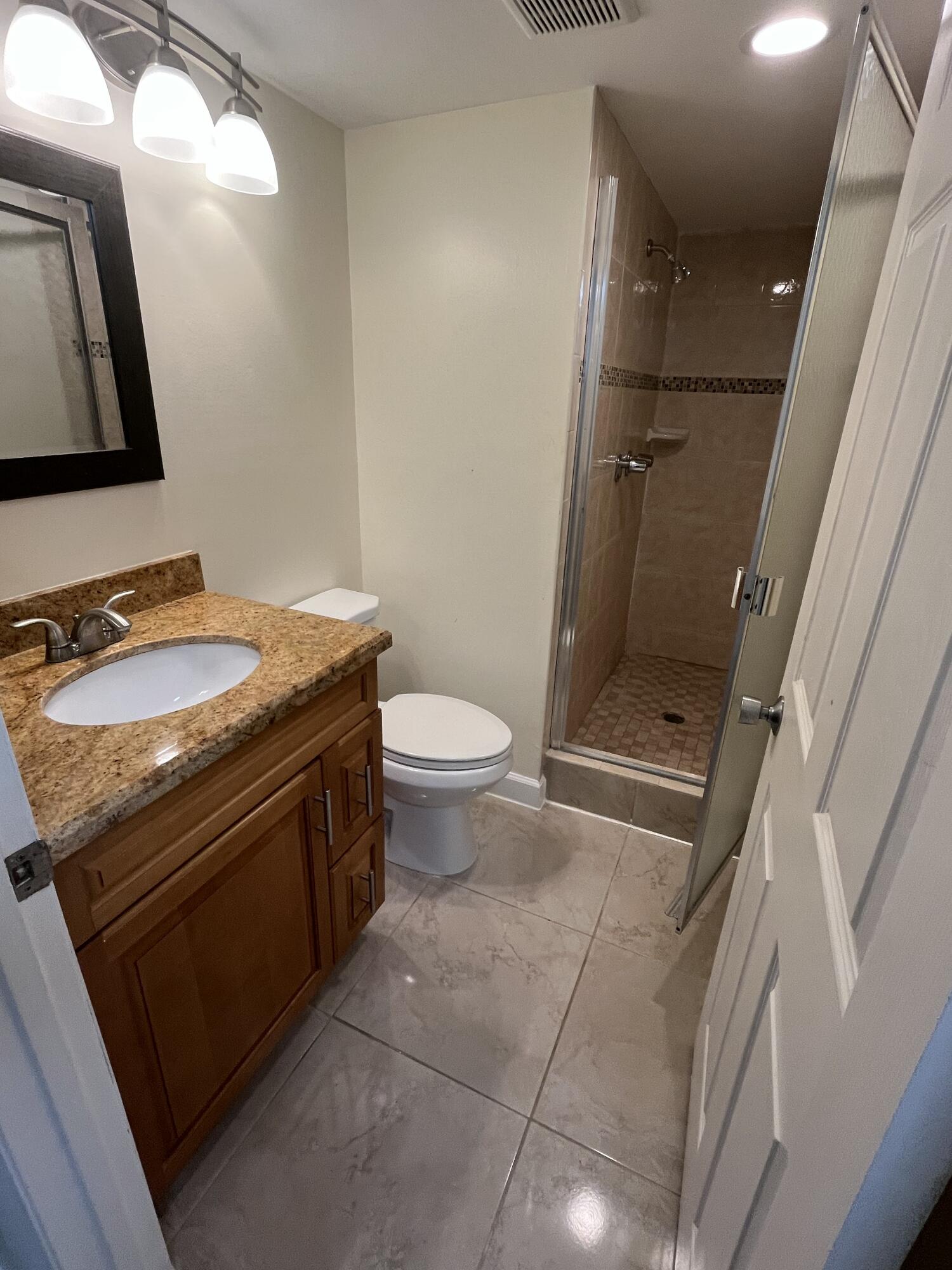 9300 Southwest 8th Street, Unit 301 Boca Raton, FL 33428 - Photo 10 of 27 a bathroom with a granite countertop sink toilet and mirror