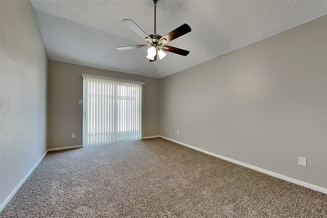 an empty room with windows and fan