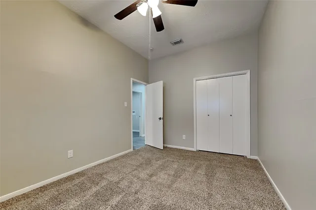 a view of an empty room and chandelier fan