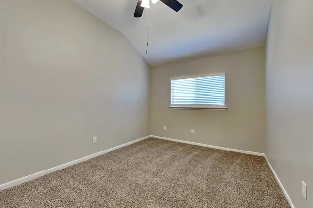 an empty room with windows and chandelier fan