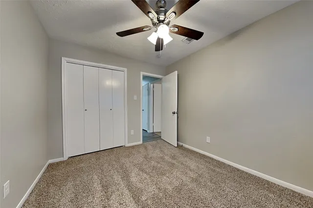 a view of an empty room and chandelier fan
