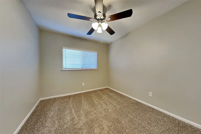 an empty room with a chandelier fan and windows