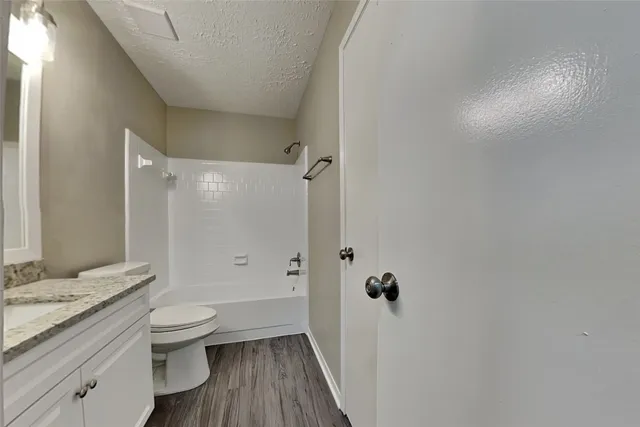 a bathroom with a granite countertop sink a toilet and shower