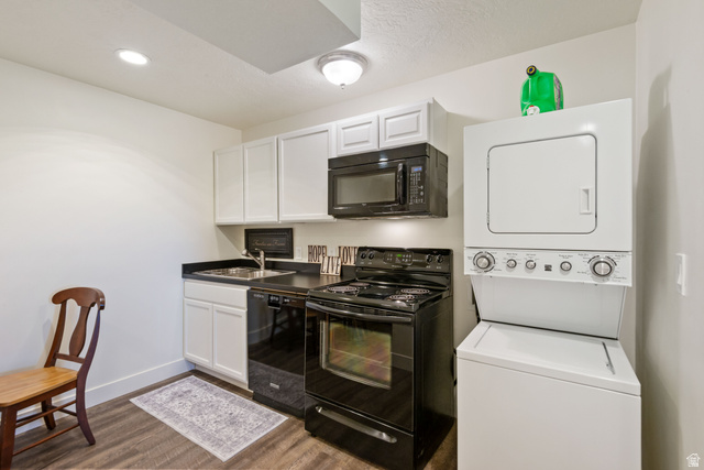 1900 North 100 East Provo, UT 84604 - Photo 38 of 49 Compact kitchen area featuring white upper and lower cabinetry, a black appliance suite including a range and microwave, dark countertops, and a full-size stacked washer and dryer unit