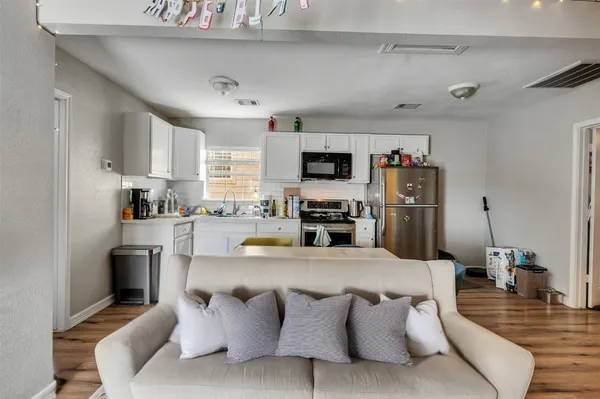 a living room with stainless steel appliances furniture and a kitchen view