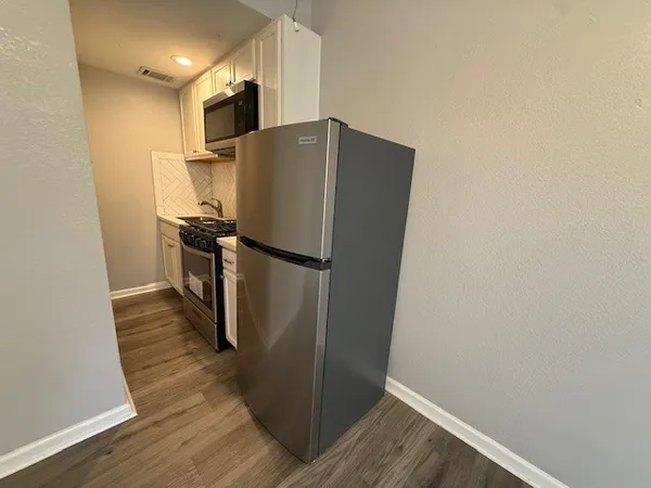 a view of a refrigerator in kitchen and wooden floor