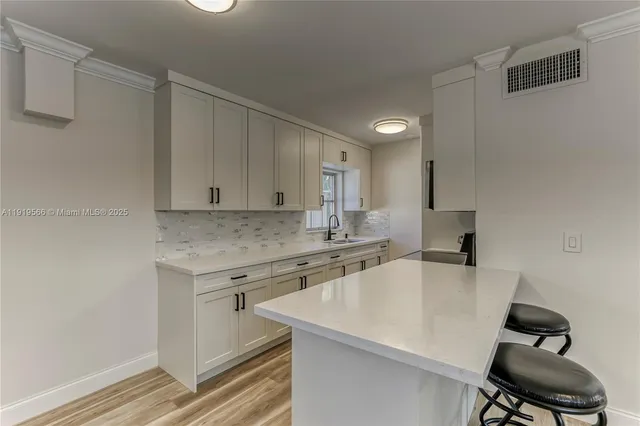 a kitchen with a sink a stove and white cabinets