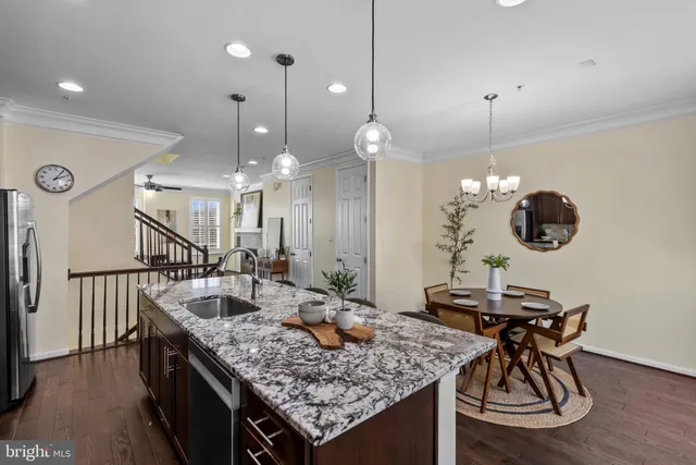 a kitchen with stainless steel appliances granite countertop a sink a stove a refrigerator and chairs