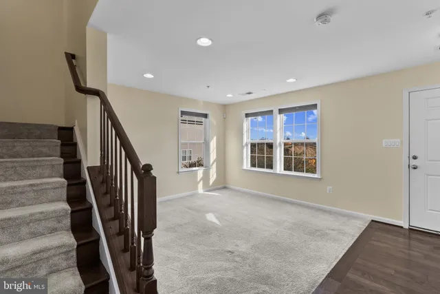 a view of an empty room with wooden floor and stairs