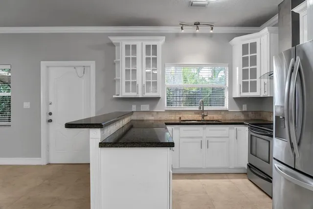 a kitchen with granite countertop a sink stainless steel appliances and window
