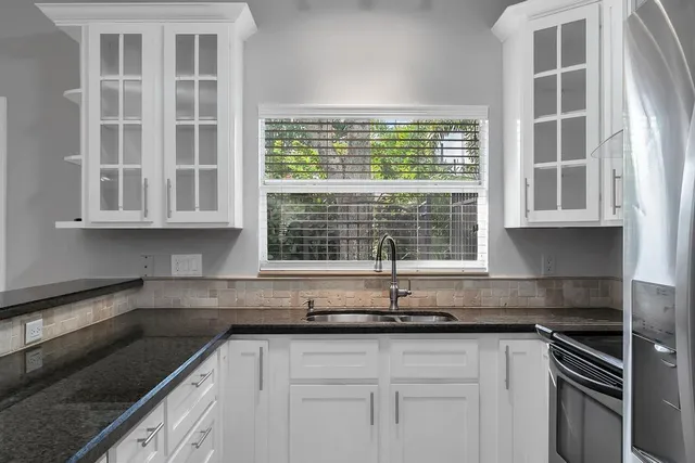 a kitchen with granite countertop a sink window and cabinets