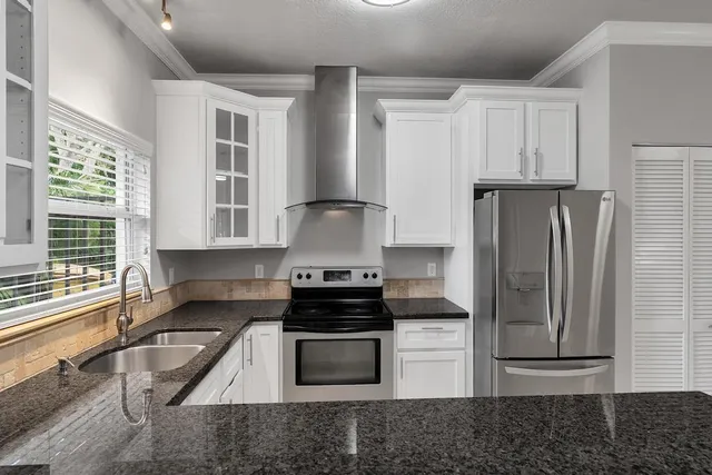a kitchen with granite countertop a refrigerator stove and sink