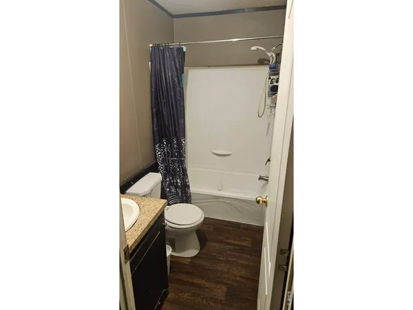 a bathroom with a granite countertop bathtub shower sink mirror and toilet