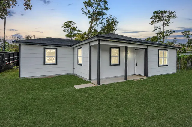 a white house that has a small yard and a lot of windows in it