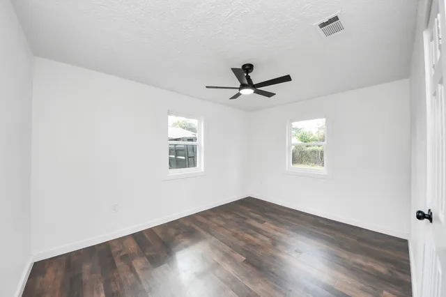 a view of a big room with wooden floor and windows