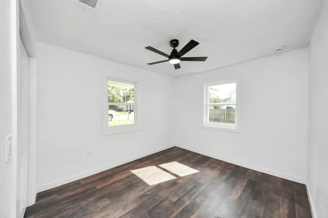 a view of empty room with wooden floor and fan