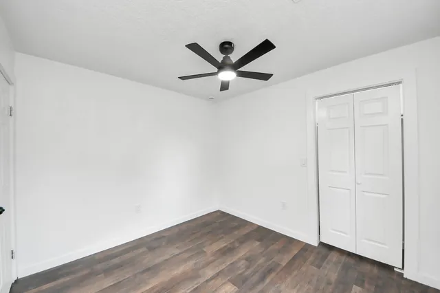 an empty room with wooden floor and ceiling fan