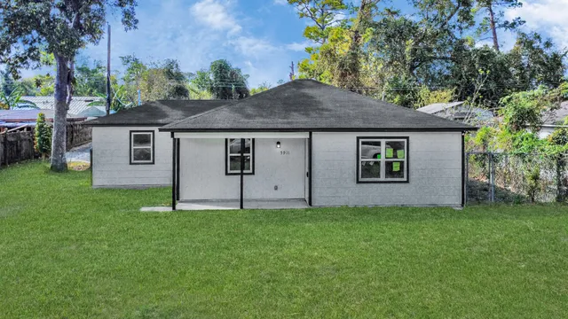 a house that is sitting in the grass with tress in the background