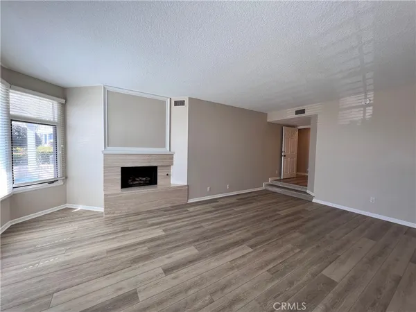 a view of empty room with wooden floor and fireplace