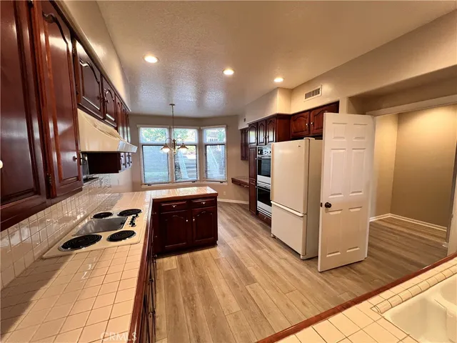 a kitchen with stainless steel appliances granite countertop a refrigerator a sink dishwasher a stove and white countertops with wooden floor