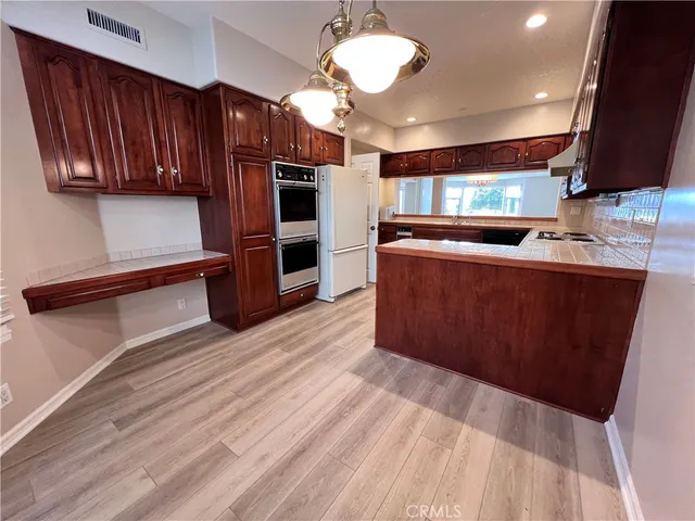 a large kitchen with stainless steel appliances a large counter top a stove and a refrigerator