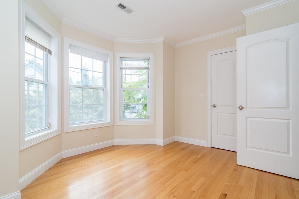 123 Russell Street, Unit 1 Waltham, MA 02453 - Photo 2 of 12 an empty room with wooden floor and windows
