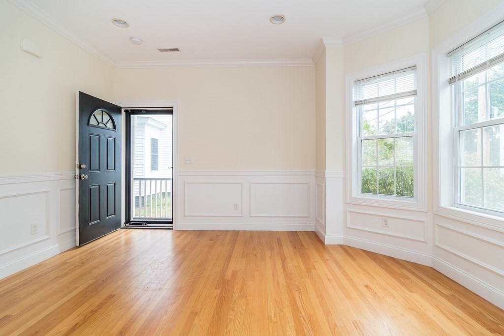 123 Russell Street, Unit 1 Waltham, MA 02453 - Photo 4 of 12 an empty room with wooden floor and windows
