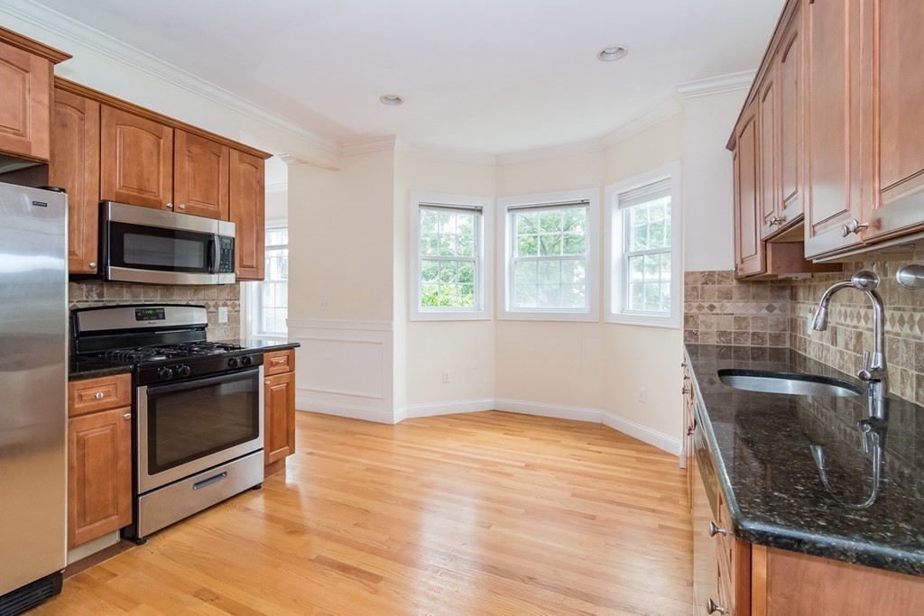 123 Russell Street, Unit 1 Waltham, MA 02453 - Photo 5 of 12 a kitchen with granite countertop a stove a sink and a microwave