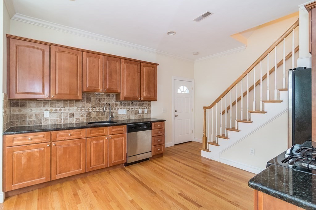 123 Russell Street, Unit 1 Waltham, MA 02453 - Photo 6 of 12 a kitchen with stainless steel appliances granite countertop a stove top oven a sink dishwasher and cabinets with wooden floor