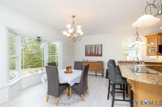 a dining room with wooden floor a chandelier a wooden table and chairs