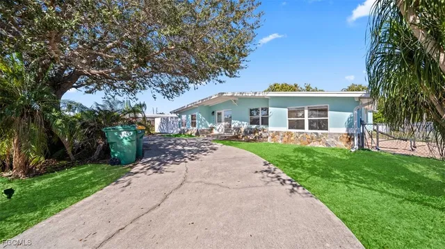 a front view of a house with a garden and trees