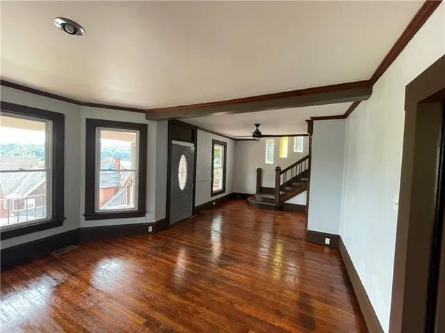 a view of empty room with wooden floor and fan