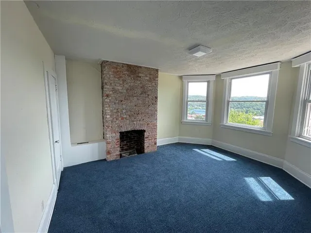 an empty room with windows and fireplace