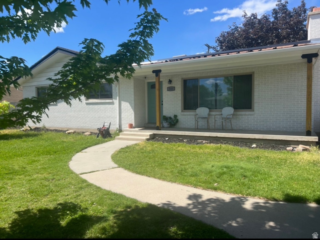 541 Mingo View Avenue Sandy, UT 84070 - Photo 1 of 16 White brick exterior featuring a covered front porch with natural wood posts, a light teal entry door, and a concrete walkway