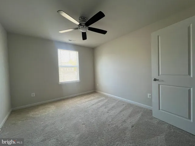 an empty room with ceiling fan and windows