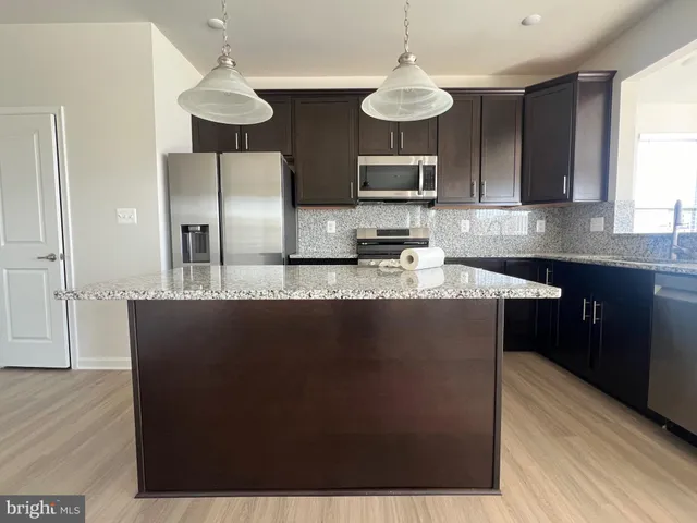 a kitchen with stainless steel appliances a refrigerator a sink a stove a microwave and wooden floor