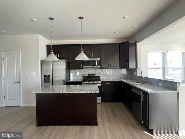 a kitchen with stainless steel appliances granite countertop a sink a stove a refrigerator and cabinets