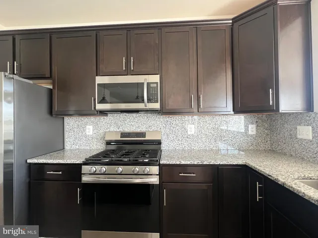 a kitchen with granite countertop wooden cabinets and stainless steel appliances