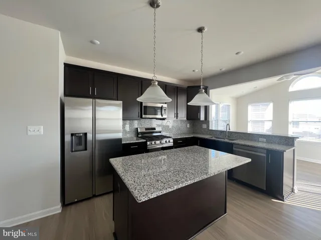 a kitchen with stainless steel appliances granite countertop a sink a stove a refrigerator and island