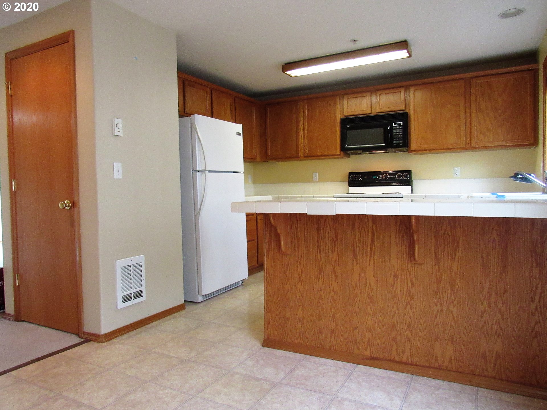 1244 Southwest 160th Avenue, Unit 101 Beaverton, OR 97006 - Photo 4 of 24 a kitchen with stainless steel appliances a refrigerator a stove a microwave and cabinets