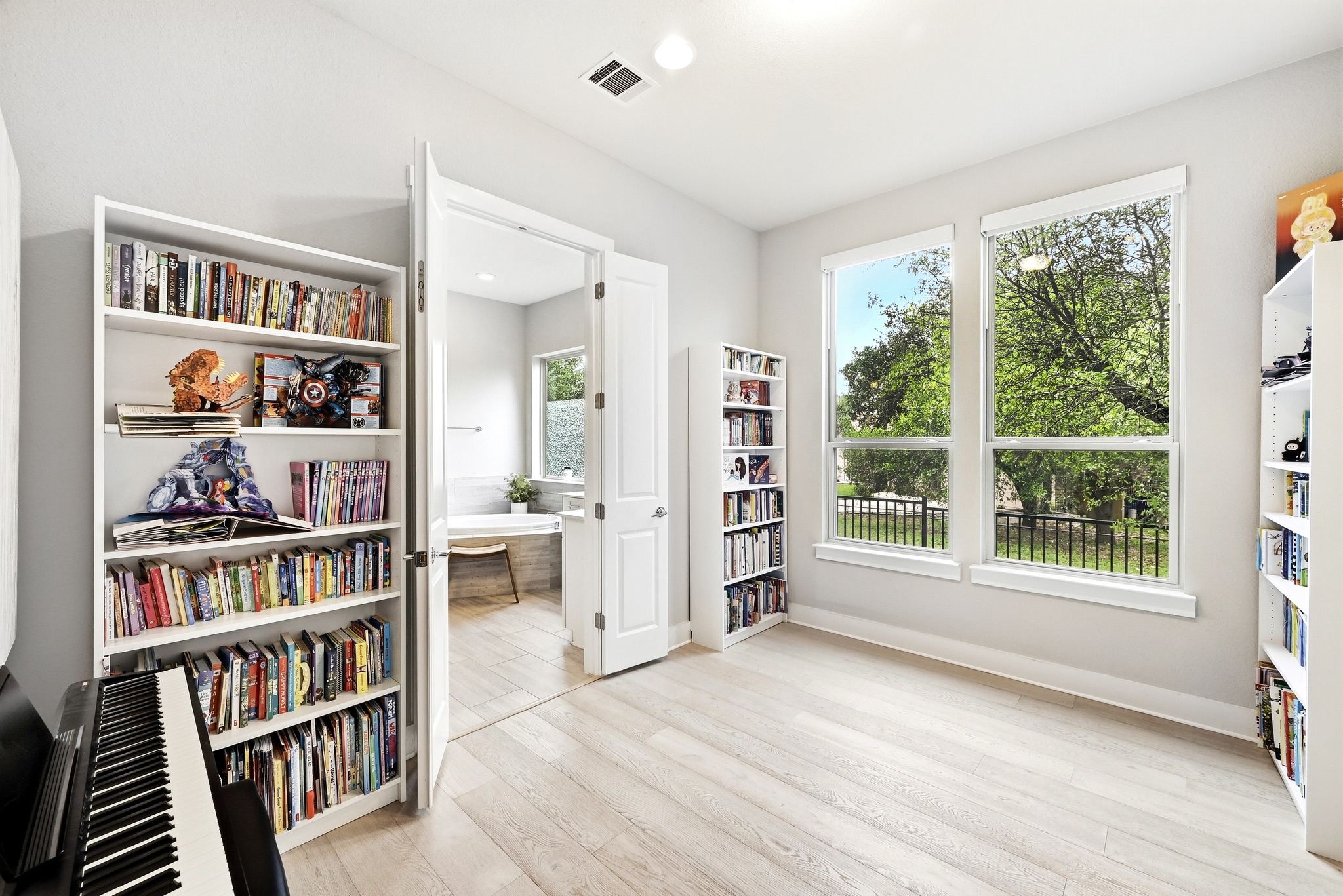 9008 Harper Rae Drive Austin, TX 78717 - Photo 19 of 39 Bright room featuring two large windows, light wood-finish flooring, recessed lighting, and a doorway opening to an additional space with a built-in desk