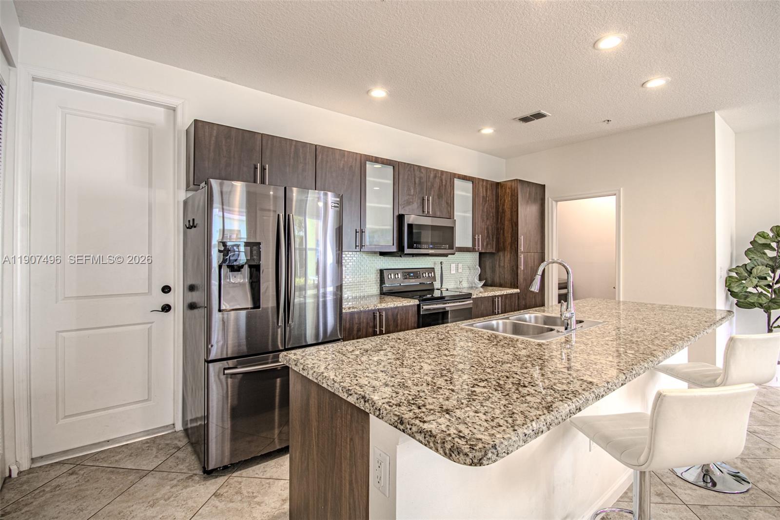 1430 Northwest 48th Drive Boca Raton, FL 33431 - Photo 11 of 33 a kitchen with kitchen island granite countertop a refrigerator and a sink