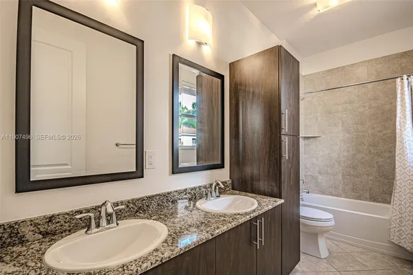a bathroom with a double vanity sink toilet mirror and shower