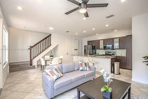 a living room with furniture kitchen view and a wooden floor