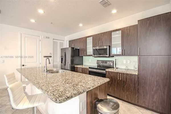 a kitchen with stainless steel appliances granite countertop a sink refrigerator and microwave