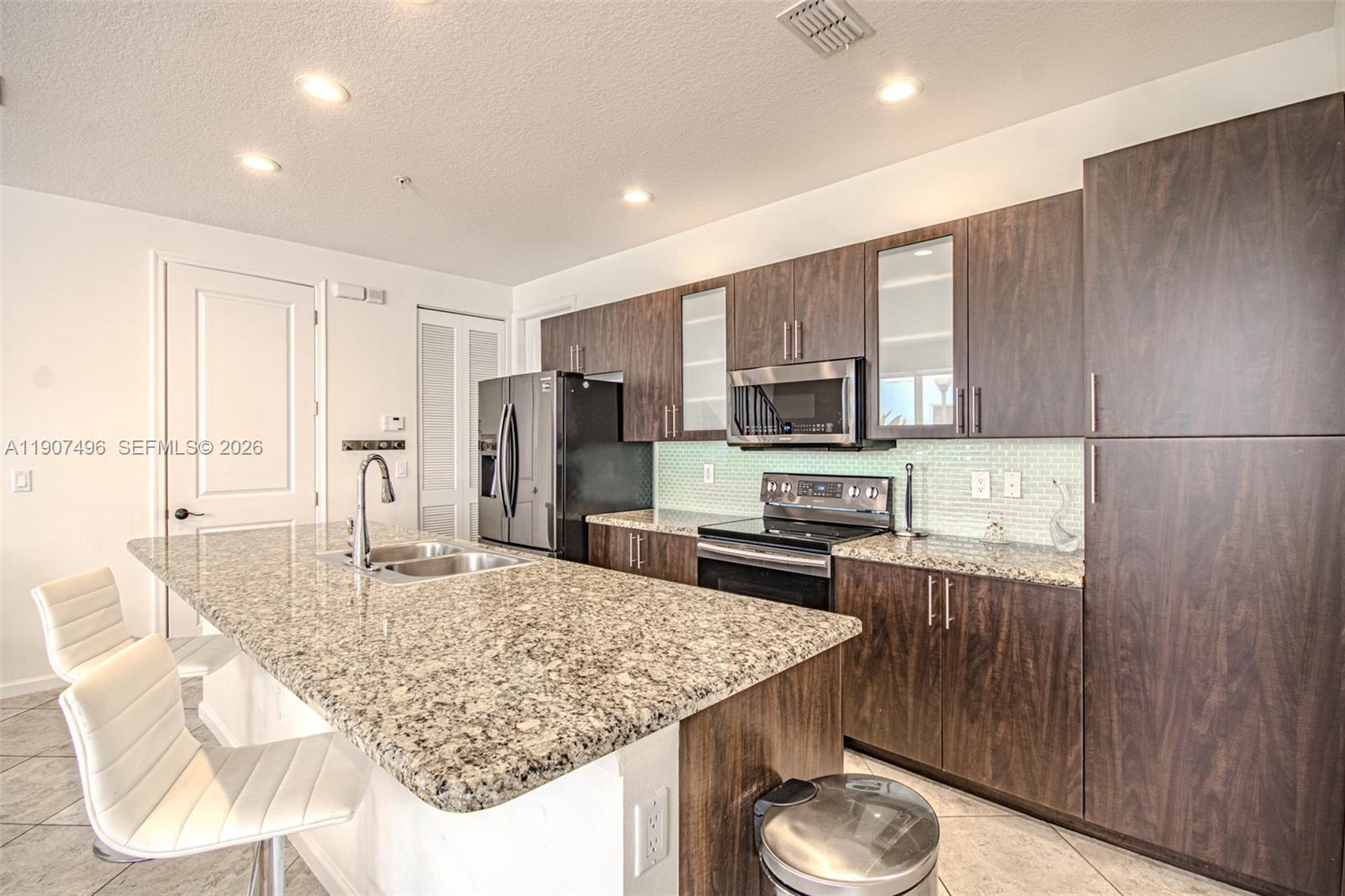 1430 Northwest 48th Drive Boca Raton, FL 33431 - Photo 10 of 33 a kitchen with stainless steel appliances granite countertop a sink refrigerator and microwave