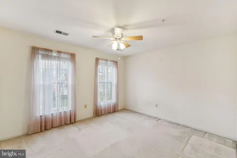 an empty room with chandelier fan and windows
