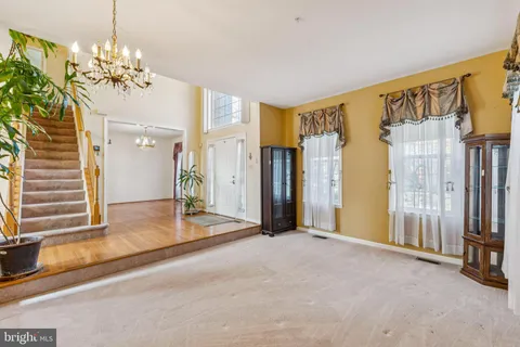 a view of a big room with chandelier front door and windows